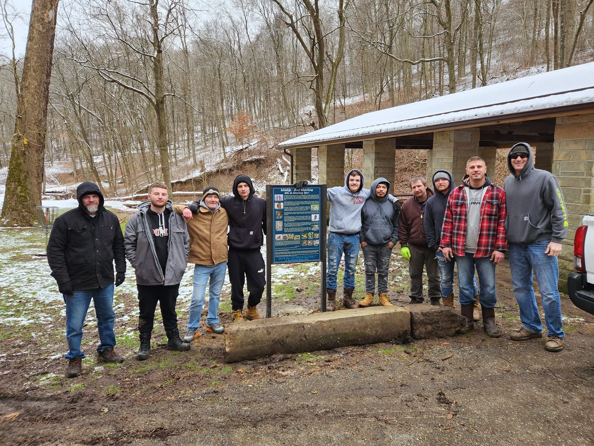 Residents and staff gathered outdoors in front of an information board